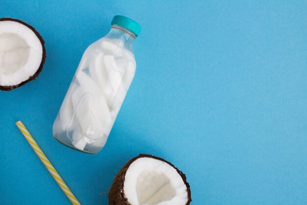 Agua de desintoxicación con coco en la botella de vidrio sobre el fondo azul.Vista superior. Copiar el espacio.