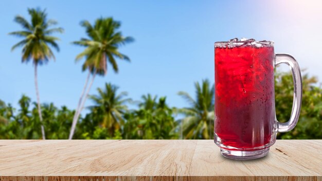 Foto Água doce de suco roselle fresca e gelada em vidro em mesa de madeira com fundo de natureza de paisagem de praia bebidas saudáveis de verão com gelo