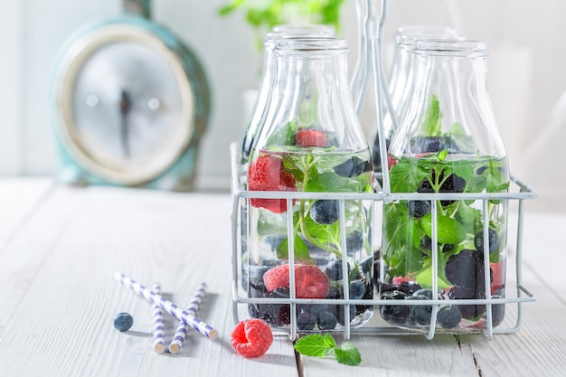 Agua dulce en botella con bayas y hojas de menta.