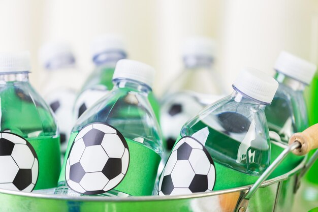 Agua embotellada en bandeja metálica con hielo para fiesta de fútbol.