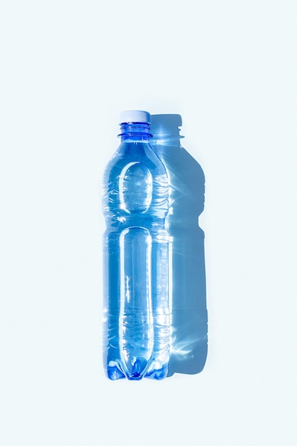 Agua embotellada Una botella de agua mineral con sombras duras sobre fondo azul Plano Vista superior Espacio de copia