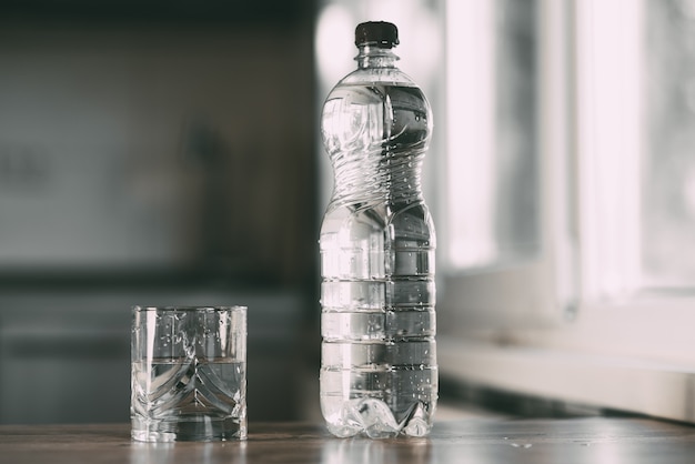 Foto agua embotellada y un vaso sobre la mesa en casa en la cocina