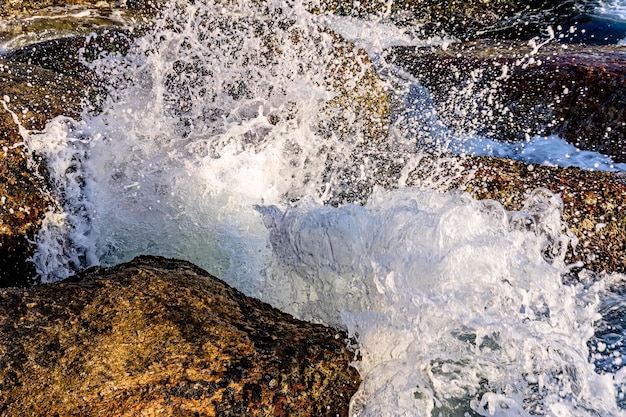 El agua y la espuma del mar salpicando en el aire con las olas chocando contra las rocas