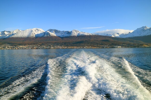 Agua espumosa en la popa del crucero con la ciudad de Ushuaia Tierra del Fuego Argentina