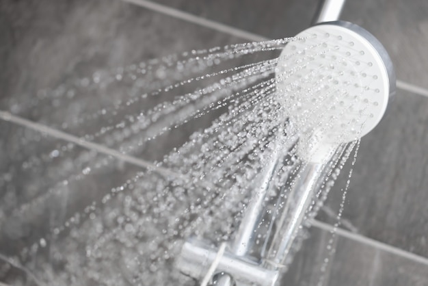 El agua fluye de la ducha de lluvia a chorros hacia el baño del hotel