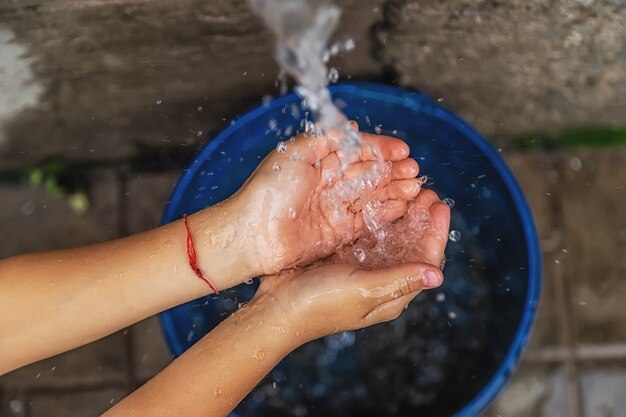 El agua fluye hacia las manos del niño. Enfoque selectivo. Niño.