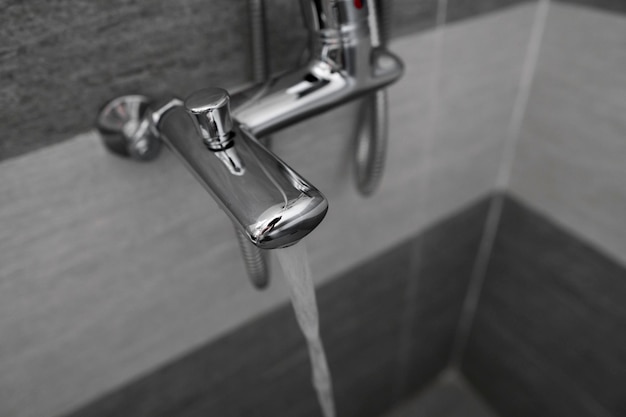 El agua fluye del mezclador Grifo de diseño moderno y ducha en el baño.