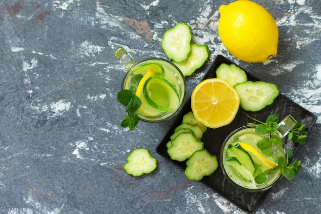 Agua fresca de desintoxicación fría y refrescante con limón y pepino sobre una mesa de piedra