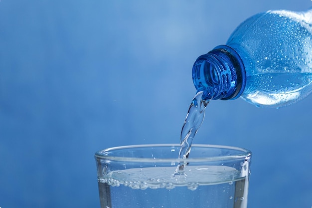 Água fresca e fresca flui do gargalo da garrafa