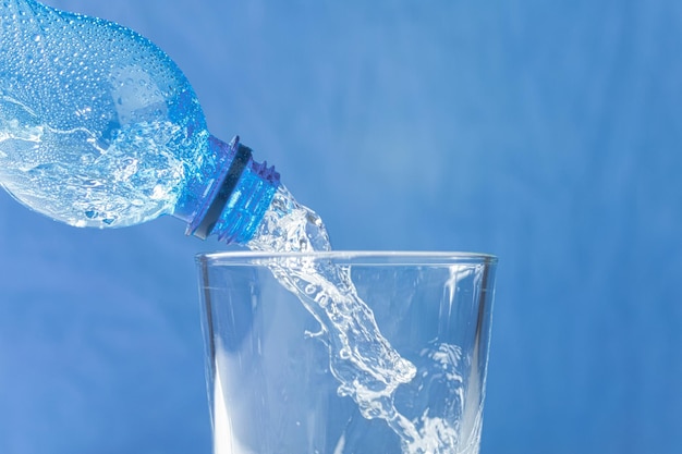 Foto el agua fresca y fresca fluye del cuello de la botella.