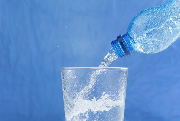 Foto el agua fresca y fresca fluye del cuello de la botella.