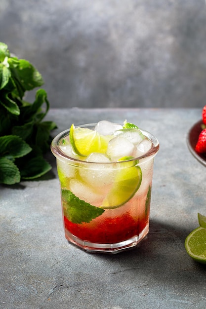 Foto agua fría de desintoxicación con menta fresa lima en el vaso con cubitos de hielo sobre fondo gris