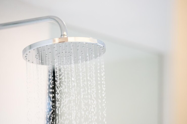 El agua fría estaba saliendo de una ducha grande en el baño con una ventana de vidrio