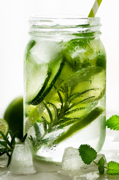 Agua fría y refrescante de desintoxicación con lima, pepino, romero y hielo en tarro de cristal.