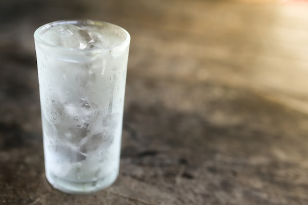 Agua fría en vidrio sobre mesa de madera.