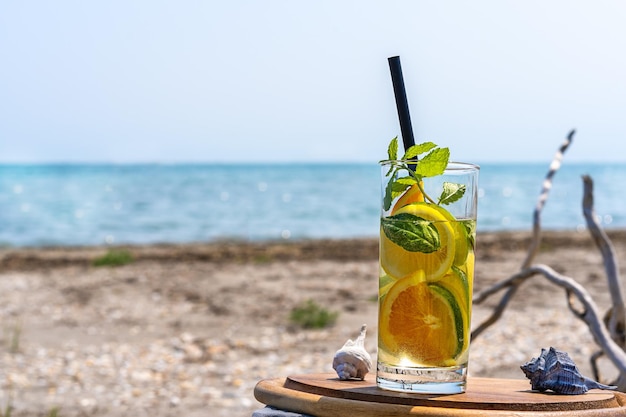 Agua infundida de desintoxicación con limón, naranjas y menta con vista a la costa del mar