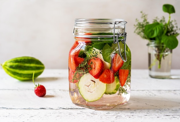 Agua infundida en frasco de vidrio con meloncella de fresa que es un híbrido de hierbas de pepino