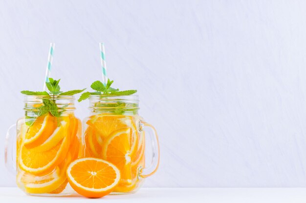 Agua infundida con frutas de naranja sobre fondo blanco Taza de una deliciosa bebida refrescante de frutas mezcladas