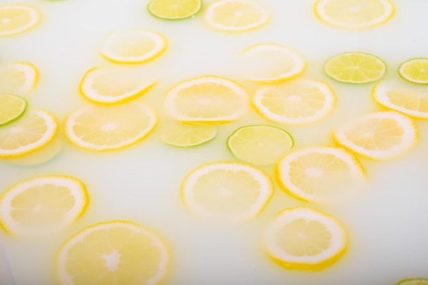 Agua jabonosa turbia en el baño con rodajas de limón y lima vista superior en cuadro completo Citrus Spa con leche en el baño para el rejuvenecimiento