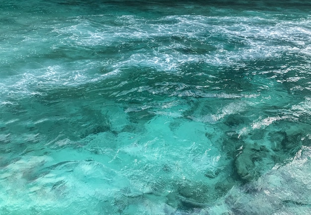 Agua de mar azul clara con espuma de salpicaduras.