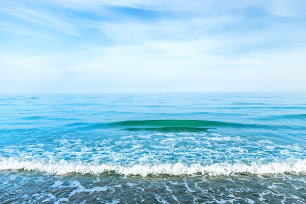 Agua de mar azul con olas, espuma y nubes blancas en el cielo. Tranquilo paisaje tropical