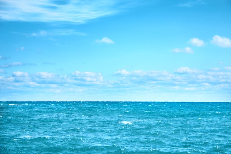 Agua de mar y cielo azul con nubes blancas. Superficie del océano de fondo natural