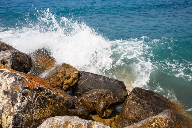 El agua de mar golpea contra las rocas rocosas y hace olas con espuma