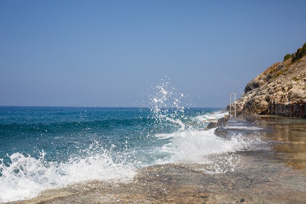 El agua de mar golpea contra las rocas rocosas y hace olas con espuma