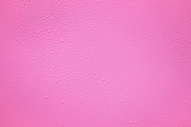 Agua o gotas de lluvia sobre una lámina de plástico rosa