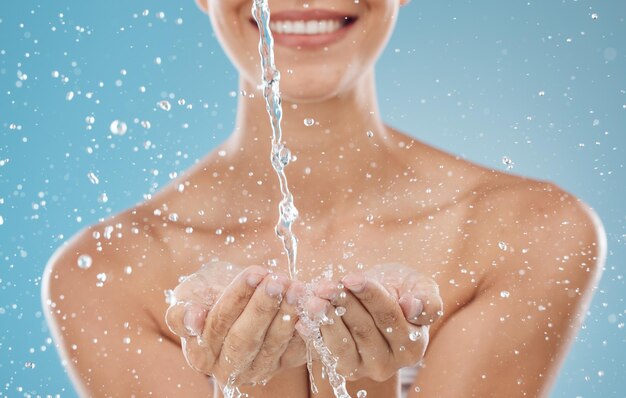 Água para a pele e mãos no fundo azul no estúdio para hidratação refrescante e limpeza facial splash bem-estar e mulher pronta para limpar o rosto para lavar, hidratar e hidratar a pele saudável