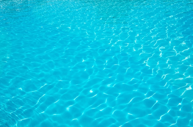 El agua de la piscina azul con reflejos del sol