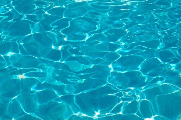 Agua de la piscina azul con reflejos del sol.