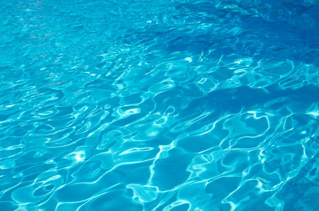 El agua de la piscina azul con reflejos del sol