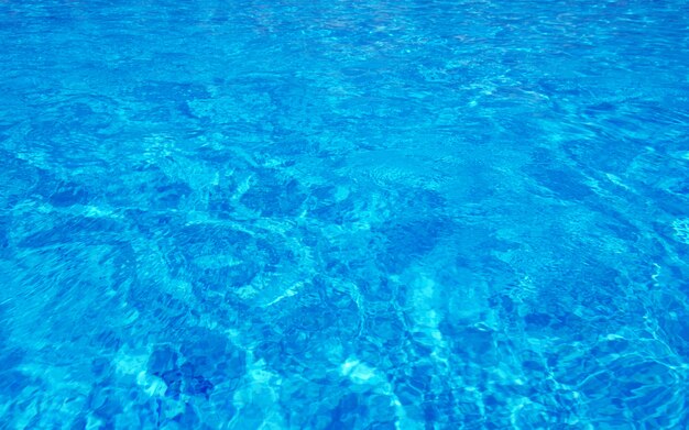 El agua de la piscina azul con reflejos del sol