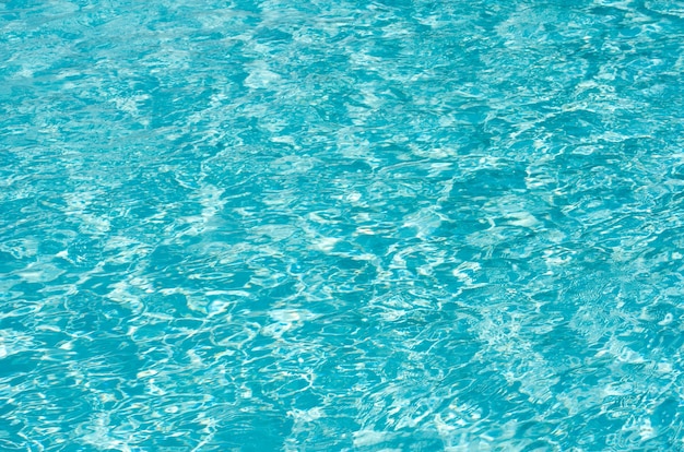 El agua de la piscina azul con reflejos del sol