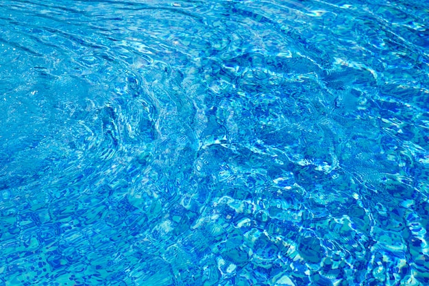 El agua de la piscina azul con reflejos del sol