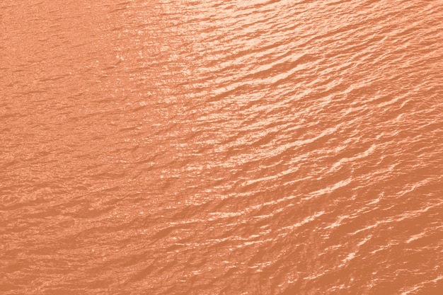 El agua de la piscina con la textura del agua de mar con tonos de melocotón con reflejos del sol es un color de moda del año