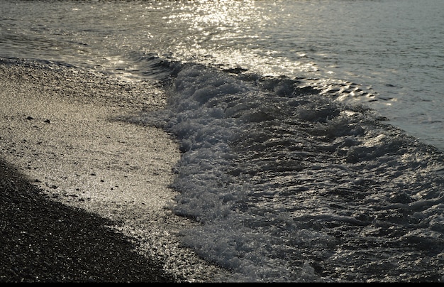 Agua de plata brillante en la playa de guijarros del mar