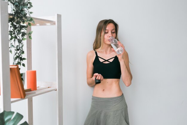 Agua potable de mujer joven deportiva después de entrenar en casa estilo de vida activo y bienestar