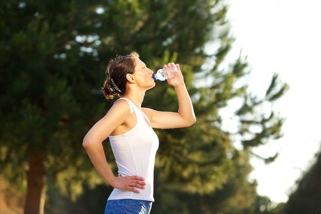 Agua potable de mujer saludable después de entrenamiento