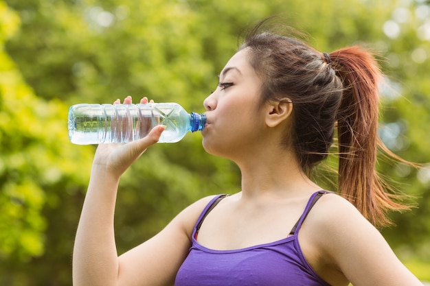 Agua potable de mujer saludable en el parque