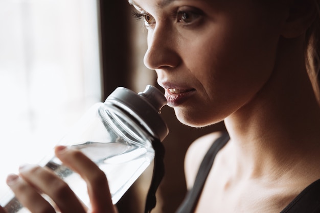 Água potável de mulher fitness muito jovem.