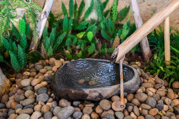 Agua que fluye de bambú en la decoración del lavabo de piedra