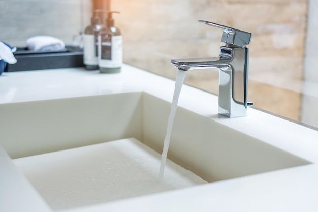 El agua que fluye hacia el lavabo moderno agua del grifo Concepto antiséptico de higiene personal y atención médica