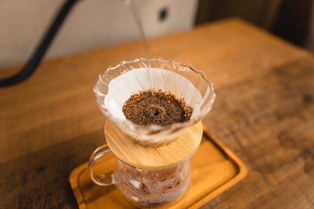 Água quente no gotejador de café acima da jarra de vidro.