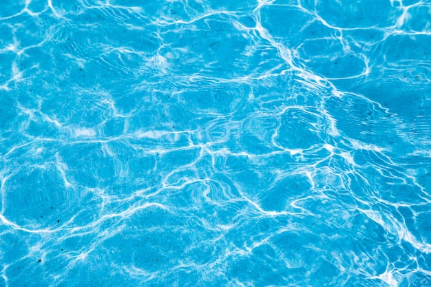 Água rasgada azul na piscina com reflexões ensolaradas.