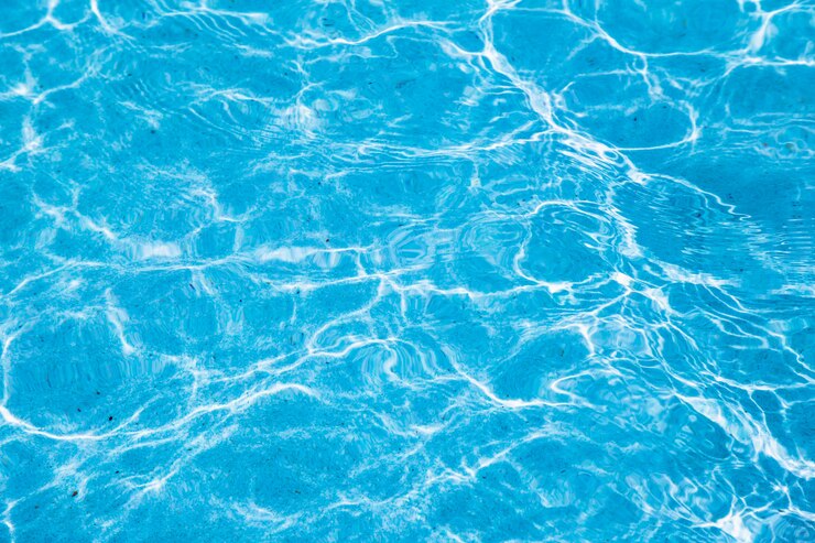 Agua rasgada azul en piscina con reflejos soleados.