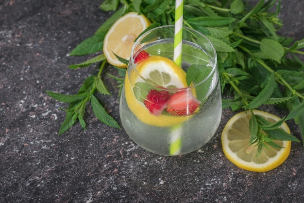 Agua refrescante con menta limón y bayas en un vaso de vidrio