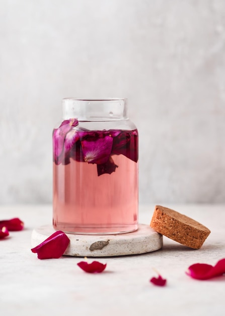 Agua de rosas casera en una botella de vidrio con pétalos de rosa Concepto de belleza y cuidado