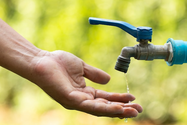 Foto agua de tabulación vertida en mano sobre la naturaleza.